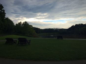 Empty bench on field against sky