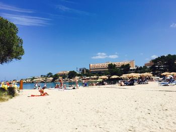 People at beach against blue sky