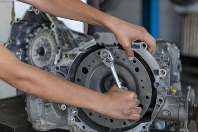 A close-up of teenager repairman repairing a gearbox of a used car in an auto repair shop. 