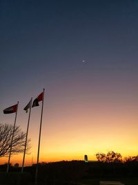 Silhouette of flags against sky during sunset