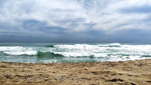 Scenic view of sea against cloudy sky at dusk