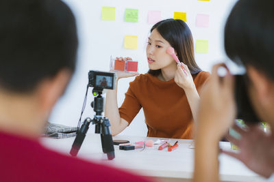 Female video blogger applying in front of camera