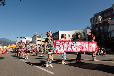 People on street against clear blue sky