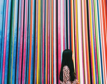 Side view of woman against colorful stripped wall