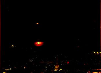 Illuminated city against sky at night