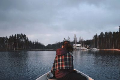 Rear view of man sitting on boat against sky