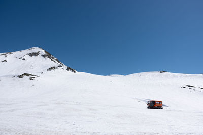 Scenic view of snow covered mountains against clear blue sky