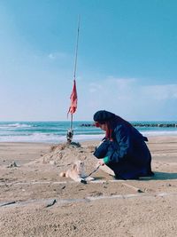 Side view of man sitting on beach