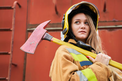 Portrait of young woman standing against yellow wall