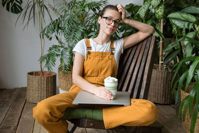 Portrait of woman with laptop sitting at home