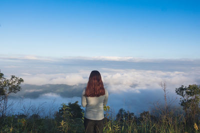 Rear view of woman standing against cloudy sky