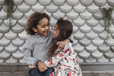 Cute siblings smiling and laughing at each other while hugging outside