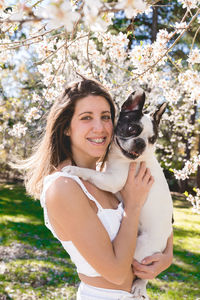 Portrait of young woman with dog on field