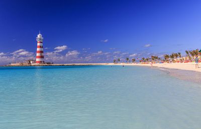 Lighthouse amidst sea and buildings against sky