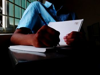 Boy writing in book while sitting on bench at school