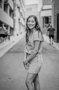 Portrait of young smiling woman standing on street 