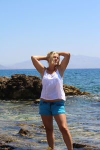 Beautiful woman posing at beach against clear sky during summer