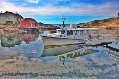 Boats moored on sea by buildings against sky