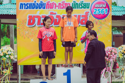 Full length of a smiling girl standing against the wall