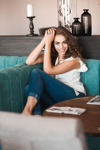 Portrait of young woman sitting on sofa at cafe