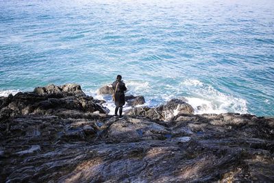 High angle view of woman standing on rocky shore