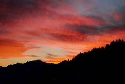 Scenic view of silhouette mountains against orange sky