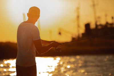 Rear view of man standing against sky during sunset