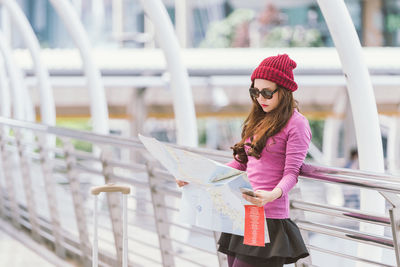 Woman looking away while standing on railing