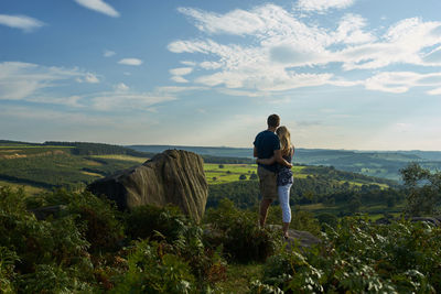 Rear view of couple standing on mountain against sky