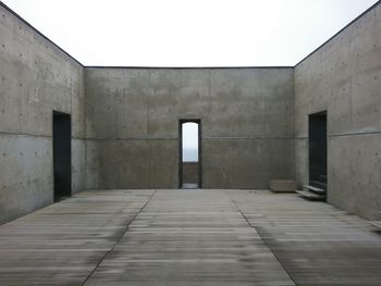 Roofless room with heavy thick concrete walls and three doors in symmetrical composition 