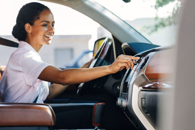 Portrait of a smiling young woman sitting on car