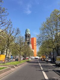 Road amidst trees in city against sky