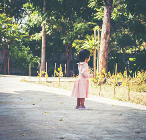 Girl walking by plants against trees