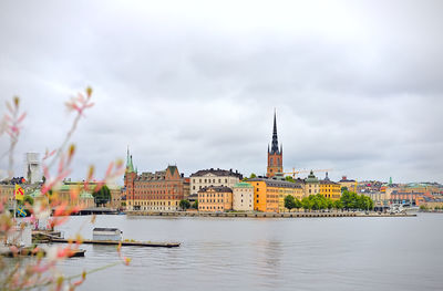 Buildings by river against sky