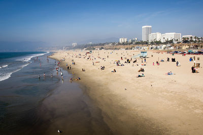 People at beach against sky in city