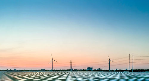 Wind turbines against sky during sunset
