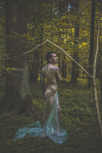 Rear view of a guy standing in the forest