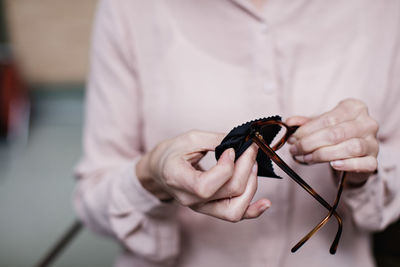 Midsection of businesswoman wiping eyeglasses at creative office