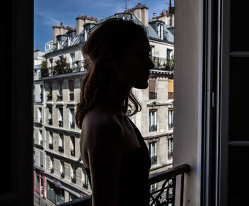 Rear view of woman looking through window