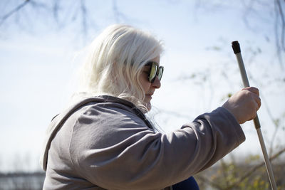 Side view of young woman holding plant