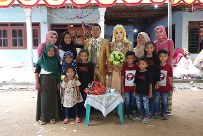 Full length of people standing with bridegroom outdoors
