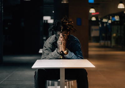 Portrait of woman sitting on table in city at night