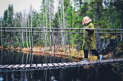 Woman standing by railing against lake