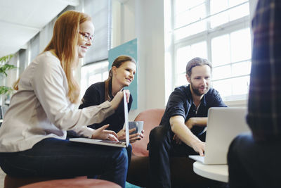 Businesspeople using laptop together in creative office