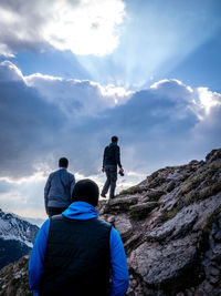 Rear view of men on mountain against sky