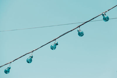 Low angle view of lighting equipment hanging against clear blue sky