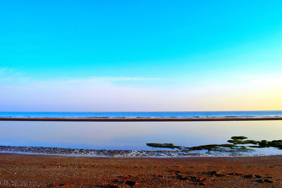 Scenic view of beach against blue sky