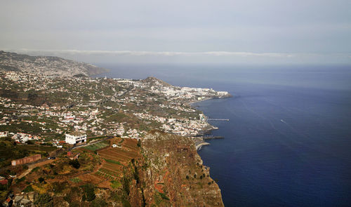 Aerial view of residential district by sea against sky