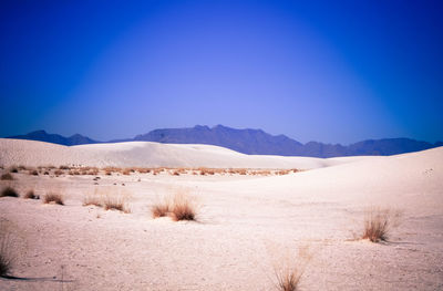 Scenic view of desert against clear blue sky