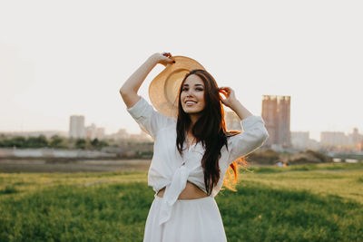 Portrait of beautiful young woman standing on land against sky